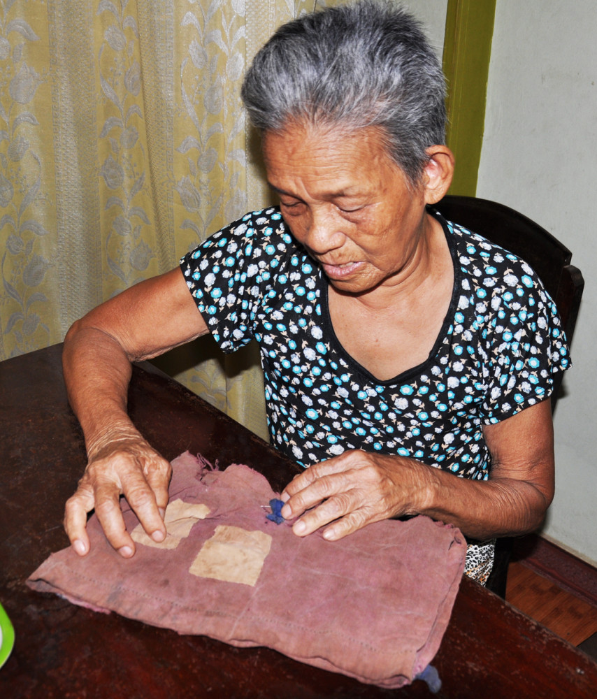 Mẹ Nguyễn Thị Em v&agrave; chiếc t&uacute;i vải c&ograve;n lại được g&igrave;n giữ hơn nửa thế kỷ của đứa con trai b&eacute; bỏng chết v&igrave; bom Mỹ tr&ecirc;n đường sơ t&aacute;n của chiến dịch K8 khi mới 7 tuổi - Ảnh: L.Đ.D